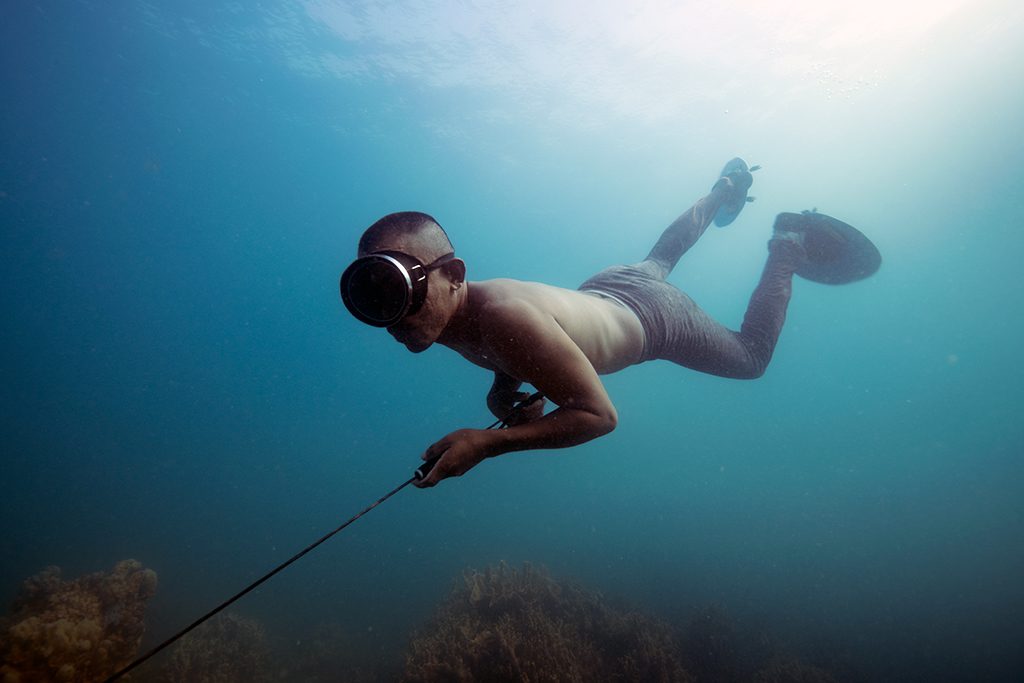 A free-diver gliding over the reef with a speargun