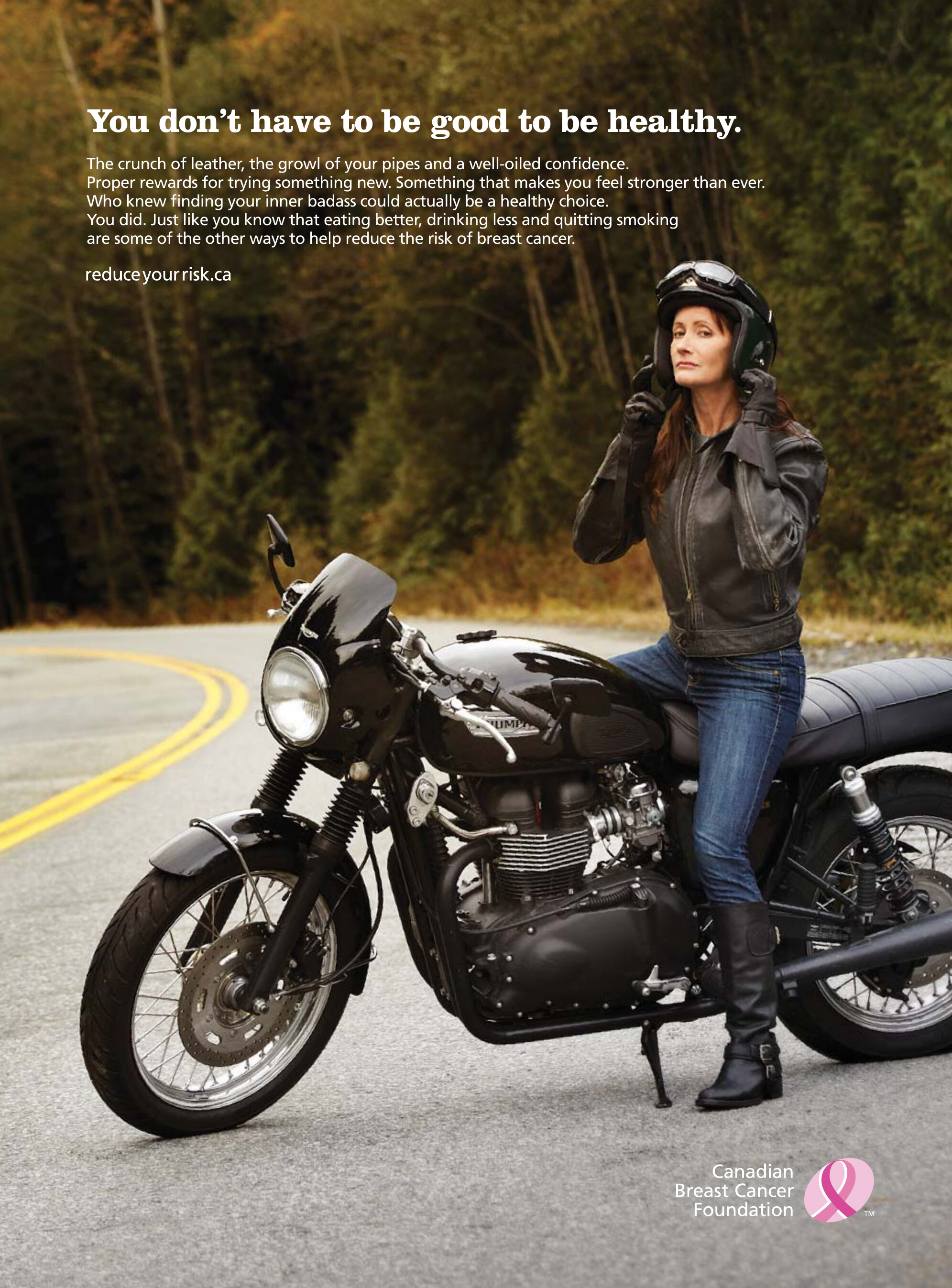 Print ad: a woman pulling on her helmet beside a black motorcycle on a forest road, headline reading you don't have to be good to be healthy