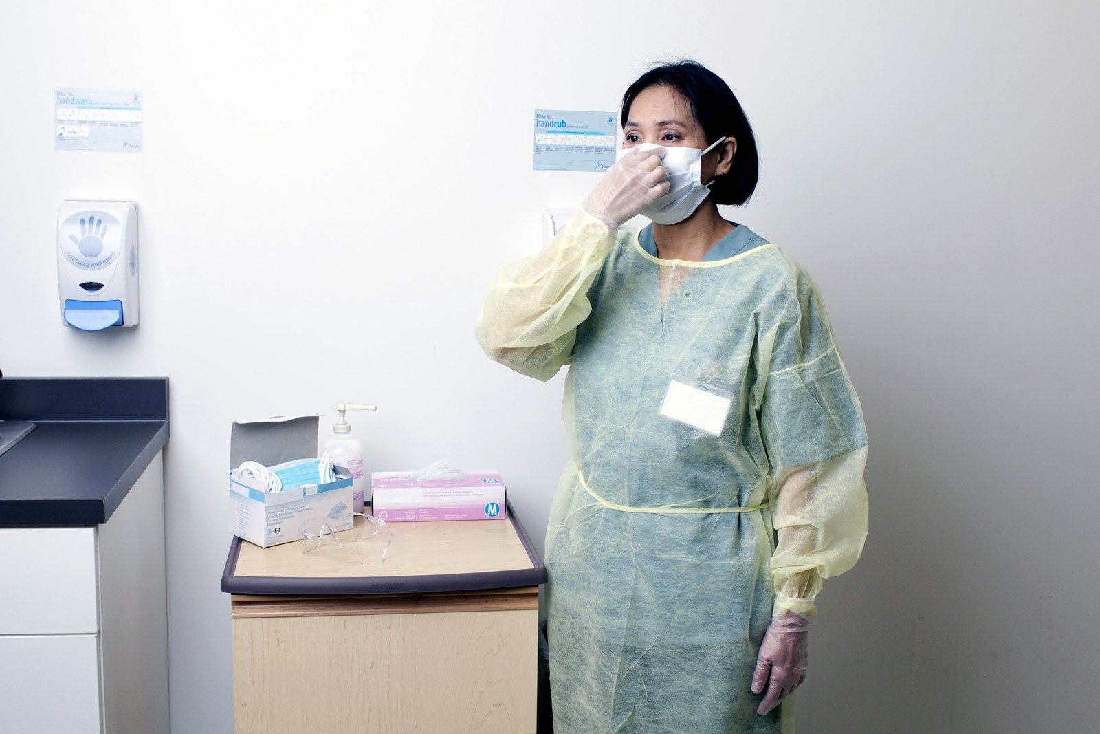 A healthcare worker in full personal protective equipment adjusting an N95 respirator, from the PHO training series