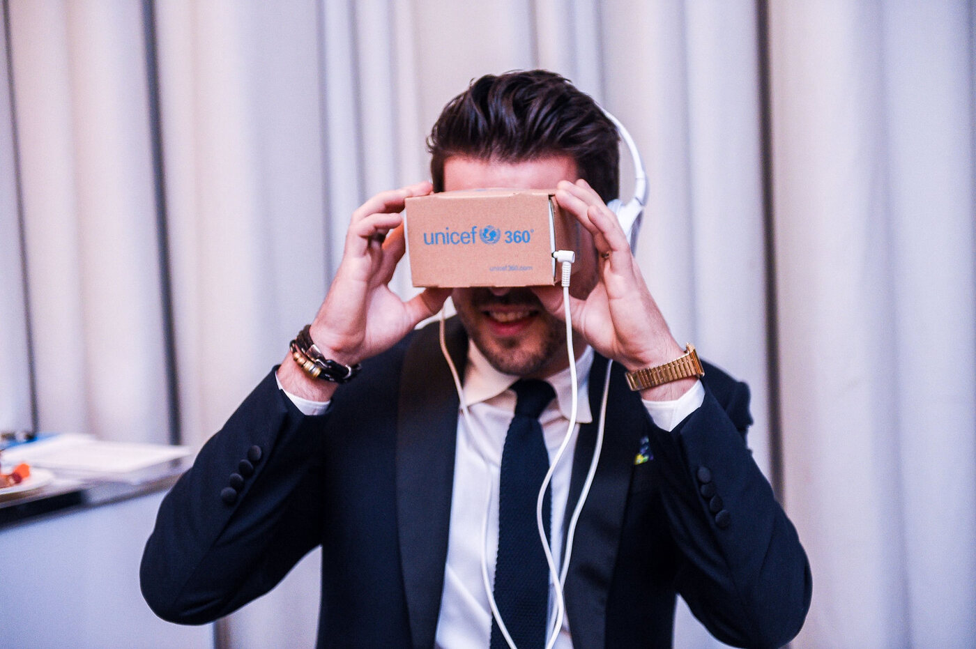 A supporter watching a UNICEF360 film through the cardboard viewer and headphones