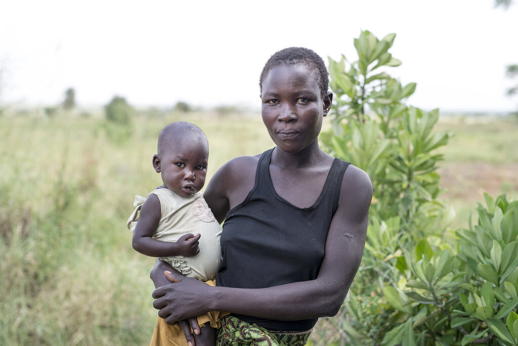 A mother holding her young child in the grasslands of the Karamoja region