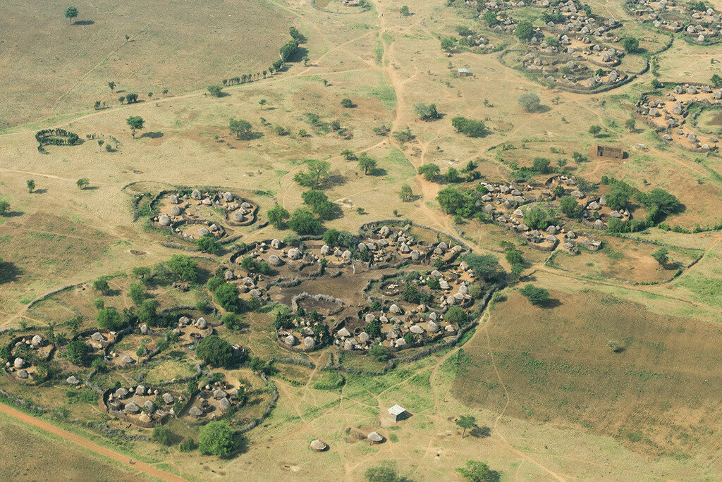 An aerial view of a Karamoja homestead, its round thatched huts ringed by stockade fencing